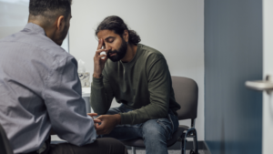 Man holding his head looking worried talking to a health professional