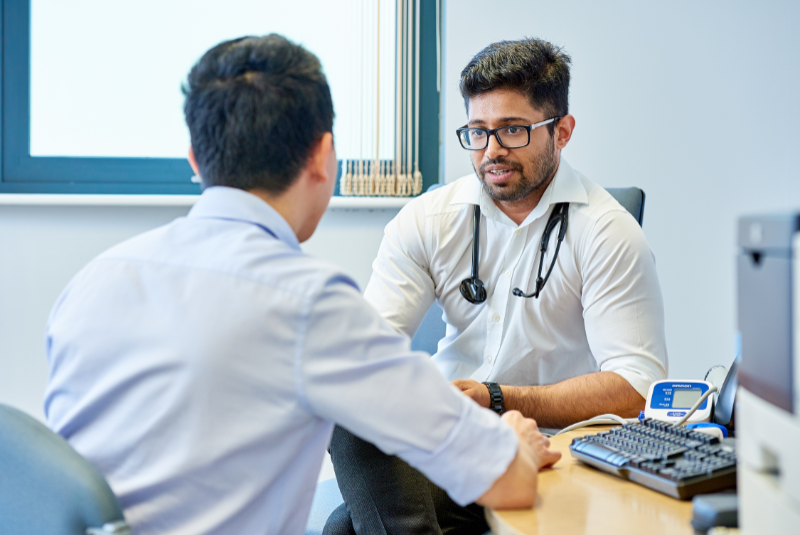 A health professional in conversation with a person who has their back to the camera.