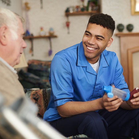 A health professional smiling and looking at a senior man.