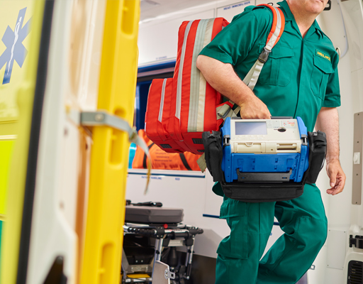 A paramedic inside an ambulance carrying a bag and rucksack.