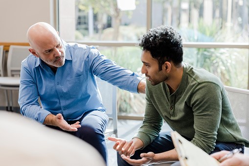 Two people sat in front of a table, in conversation.